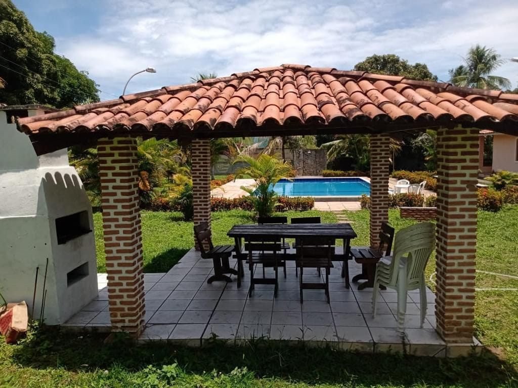 Quiosque com churrasqueira e piscina ao fundo