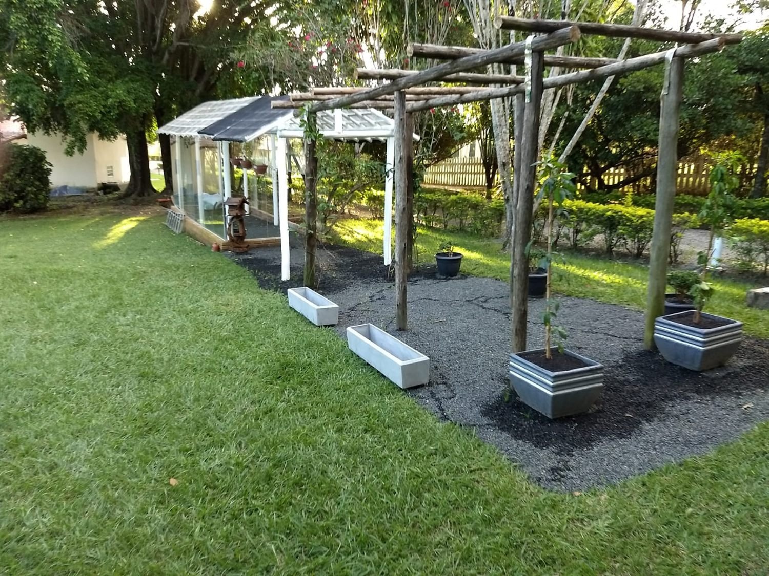 Jardim com pergolado e estufa
